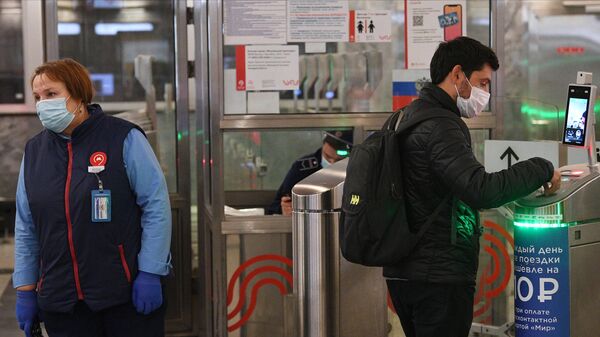 Молодой человек у турникета с установленным дистанционным тепловизором на станции метро Спартак в Москве
