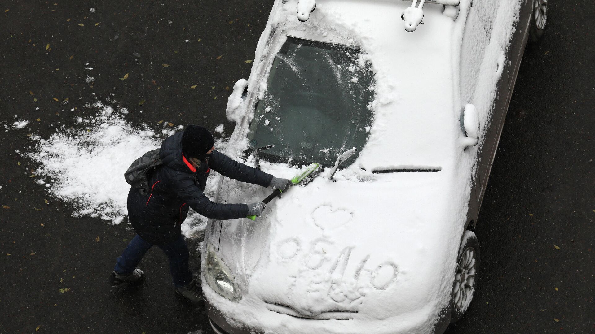 Женщина очищает автомобиль от снега после первого снегопада в городе Дивногорске Красноярского края - РИА Новости, 1920, 06.10.2020