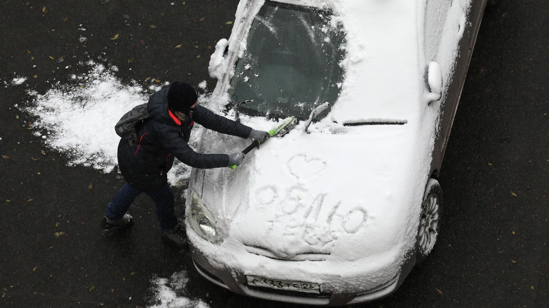 Женщина очищает автомобиль от снега после первого снегопада в городе Дивногорске Красноярского края - РИА Новости, 1920, 06.10.2020