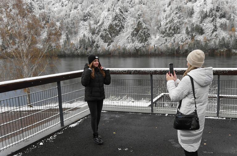 Девушки фотографируются после первого снегопада на набережной Енисея в городе Дивногорске Красноярского края