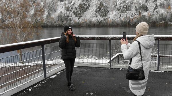 Девушки фотографируются после первого снегопада на набережной Енисея в городе Дивногорске Красноярского края