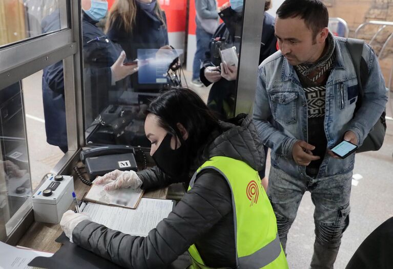 Сотрудница Московского метрополитена выписывает штраф пассажиру за несоблюдение масочного режима