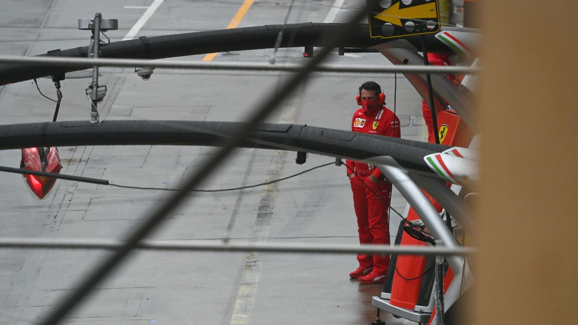 A Ferrari F1 team mechanic waits in the pit lane for the announcement whether a second practice session will take place at the Nuerburgring circuit in Nuerburg, western Germany, on October 9, 2020, ahead of the German Formula One Eifel Grand Prix. (Photo by Ina Fassbender / POOL / AFP) - РИА Новости, 1920, 09.10.2020