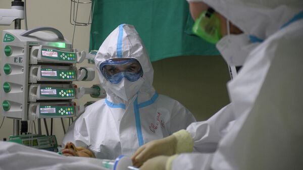 Медицинские работники оказывают помощь пациенту с COVID-19