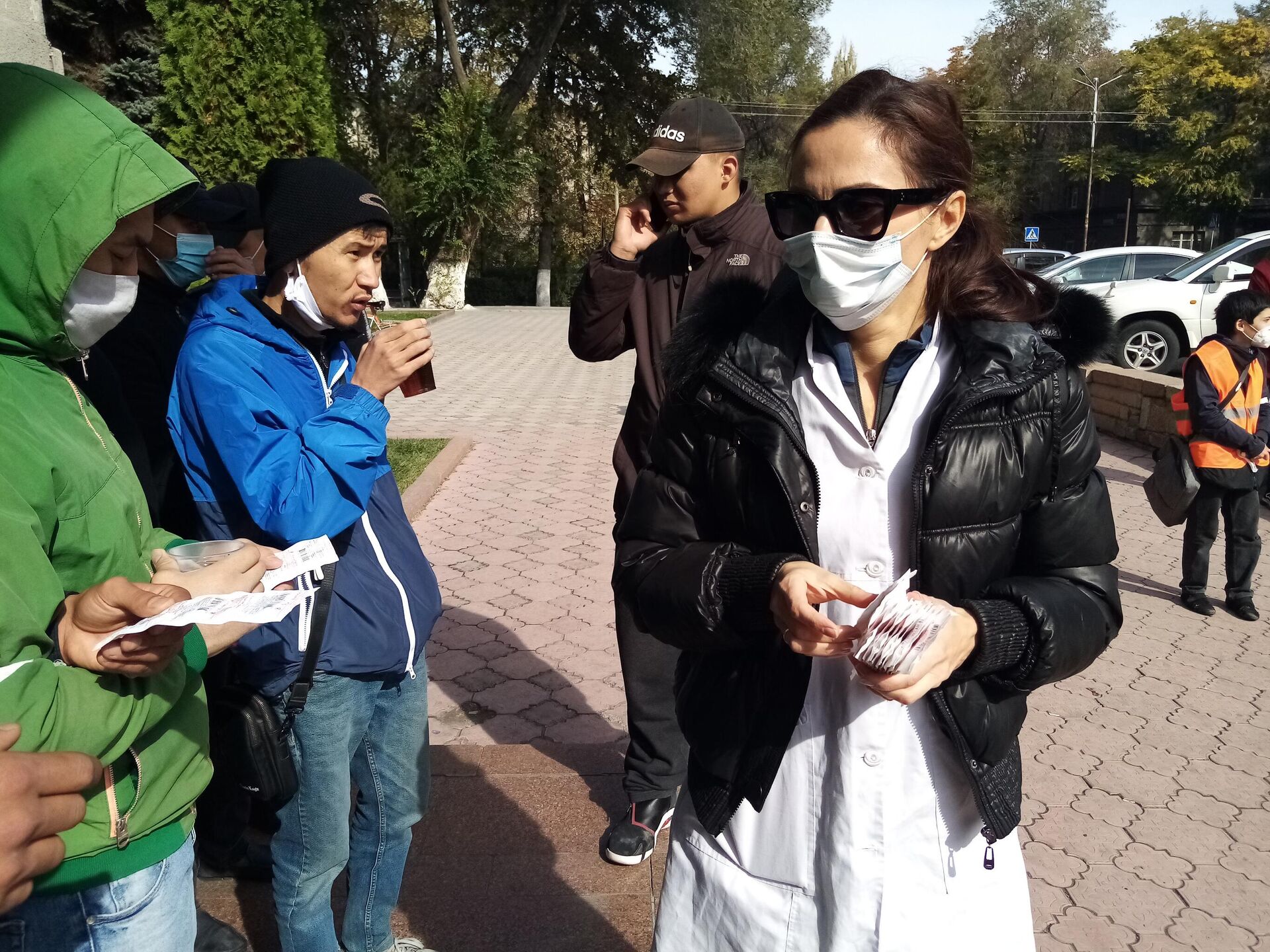Женщина раздает таблетки глюкозы участникам митинга в Бишкеке - РИА Новости, 1920, 09.10.2020