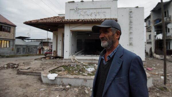 Местный житель возле дома в Степанакерте, поврежденного в результате обстрелов