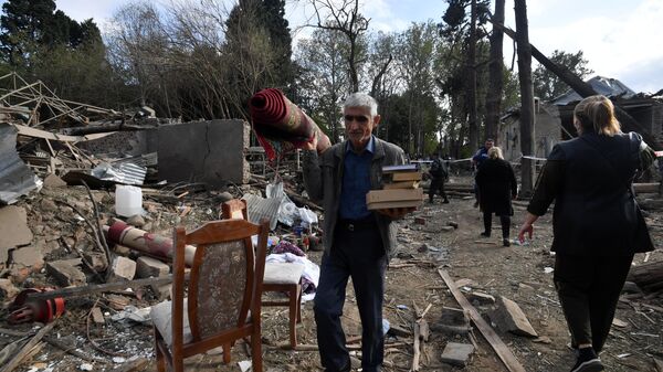 Жители собирают уцелевшие вещи на развалинах своего жилого дома, разрушенного в результате ракетного обстрела города Гянджа