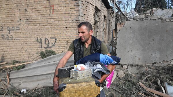 Житель собирает уцелевшие вещи на развалинах своего жилого дома, разрушенного в результате ракетного обстрела города Гянджа