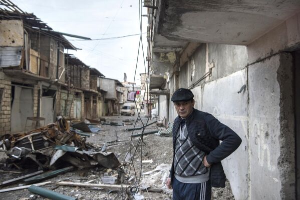 Мужчина на разрушенной улице города Степанакерт, который подвергся обстрелу