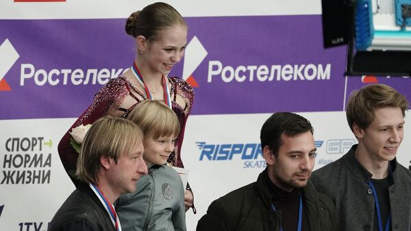 Александра Трусова (в центре на втором плане), Евгений Плющенко с сыном Александром (слева на первом плане)
