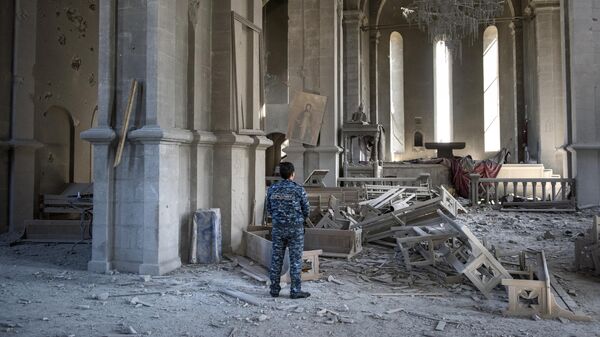 Местный житель в разрушенной обстрелом церкви в городе Шуши