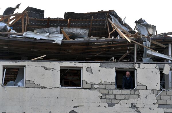 Житель в окне жилого дома, разрушенного в результате ракетного обстрела города Гянджа