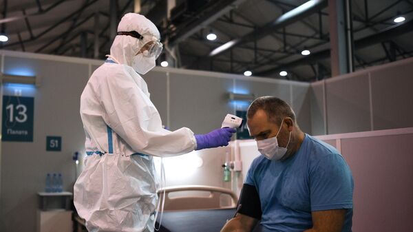Медицинский работник измеряет температуру мужчине в приемном отделении во временном госпитале для пациентов с COVID-19 в Сокольниках