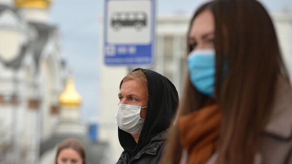 Люди в защитных масках на остановке общественного транспорта в Екатеринбурге