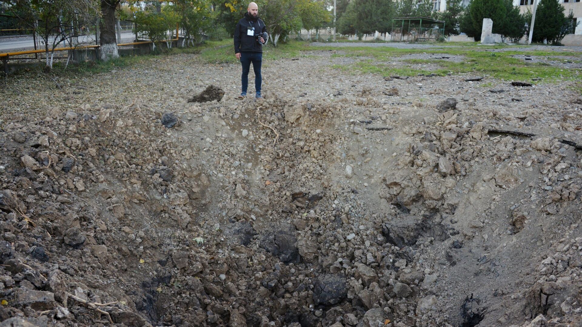 Мужчина возле воронки от упавшего снаряда возле здания школы №10 в Степанакерте - РИА Новости, 1920, 15.10.2020
