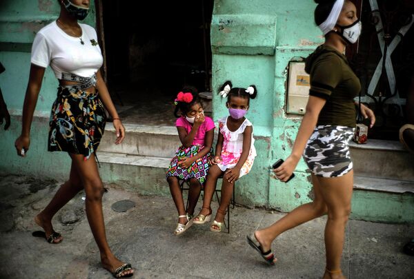 Девочки в защитных масках ждут своих родителей на улице Гаваны