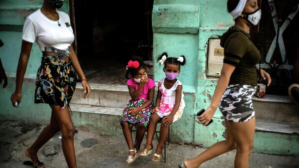 Девочки в защитных масках ждут своих родителей на улице Гаваны