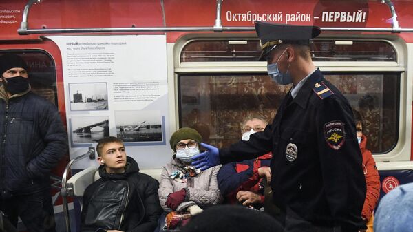 Сотрудник правоохранительных органов и пассажир без маски во время рейда по проверке соблюдения масочного режима на станции метро Красный проспект в Новосибирске