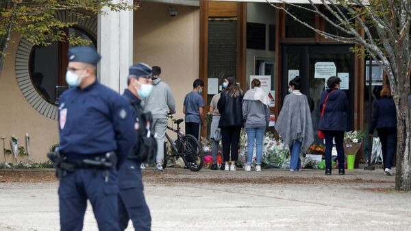 Люди несут цветы к месту, где было совершено нападение на учителя в коммуне Конфлан-Сент-Онорин, Франция