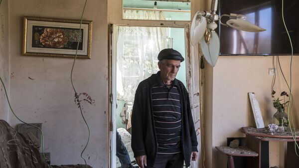 Мужчина в своем доме, поврежденном в результате ракетного обстрела селения Шош