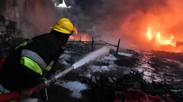 Пожарный тушит пожар на хлопковом заводе в деревне Азат Карагоинлы в Азербайджане, который возник в результате артиллерийского обстрела