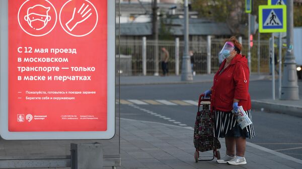 Женщина в защитной маске на остановке общественного транспорта на площади Савеловского вокзала в Москве