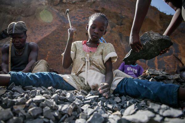 Десятилетняя девочка зарабатывает деньги,  разбивая камни молотком в Найроби, Кения 