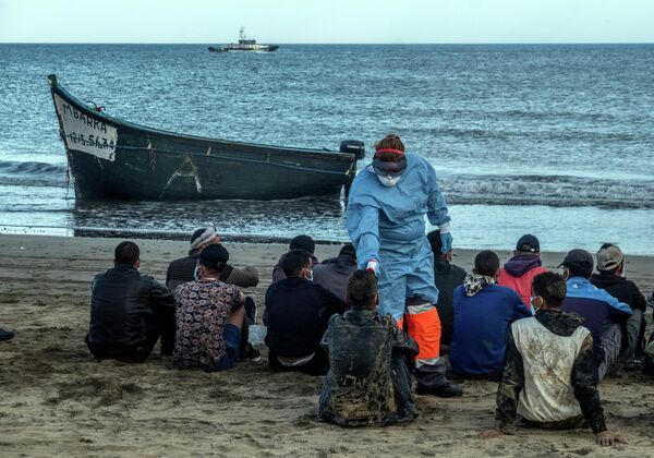 Мигрантам из Марокко проверяют температуру после прибытия на побережье Канарских островов