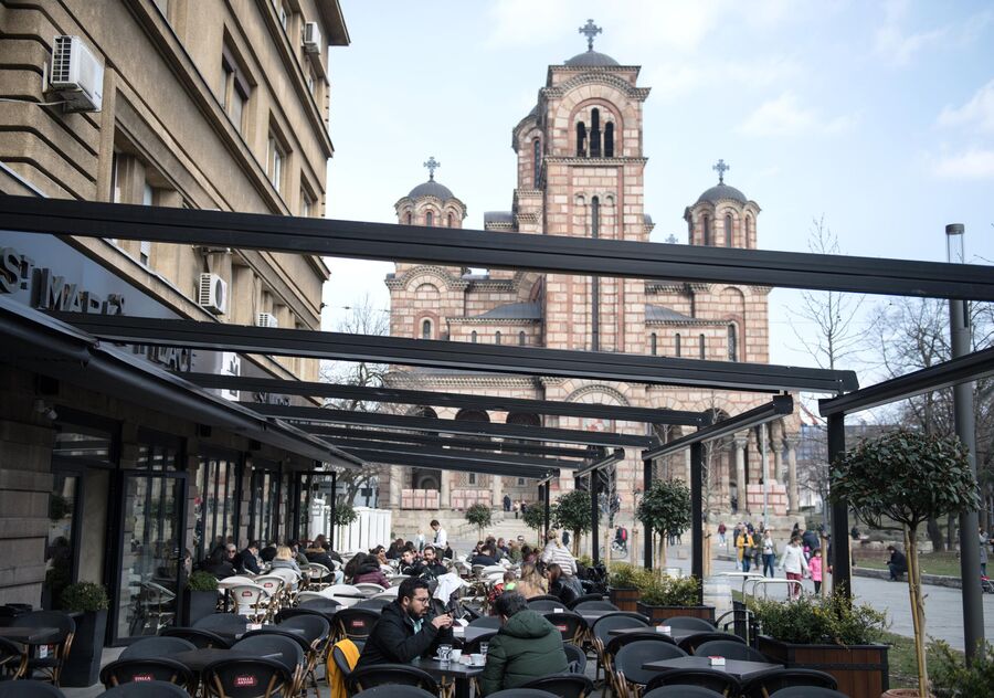 Горожане отдыхают в уличном кафе на площади перед церковью Марка Евангелиста в Белграде