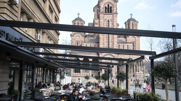 Горожане отдыхают в уличном кафе на площади перед церковью Марка Евангелиста в Белграде