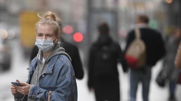 Девушка в защитной маске на одной из улиц в Москве