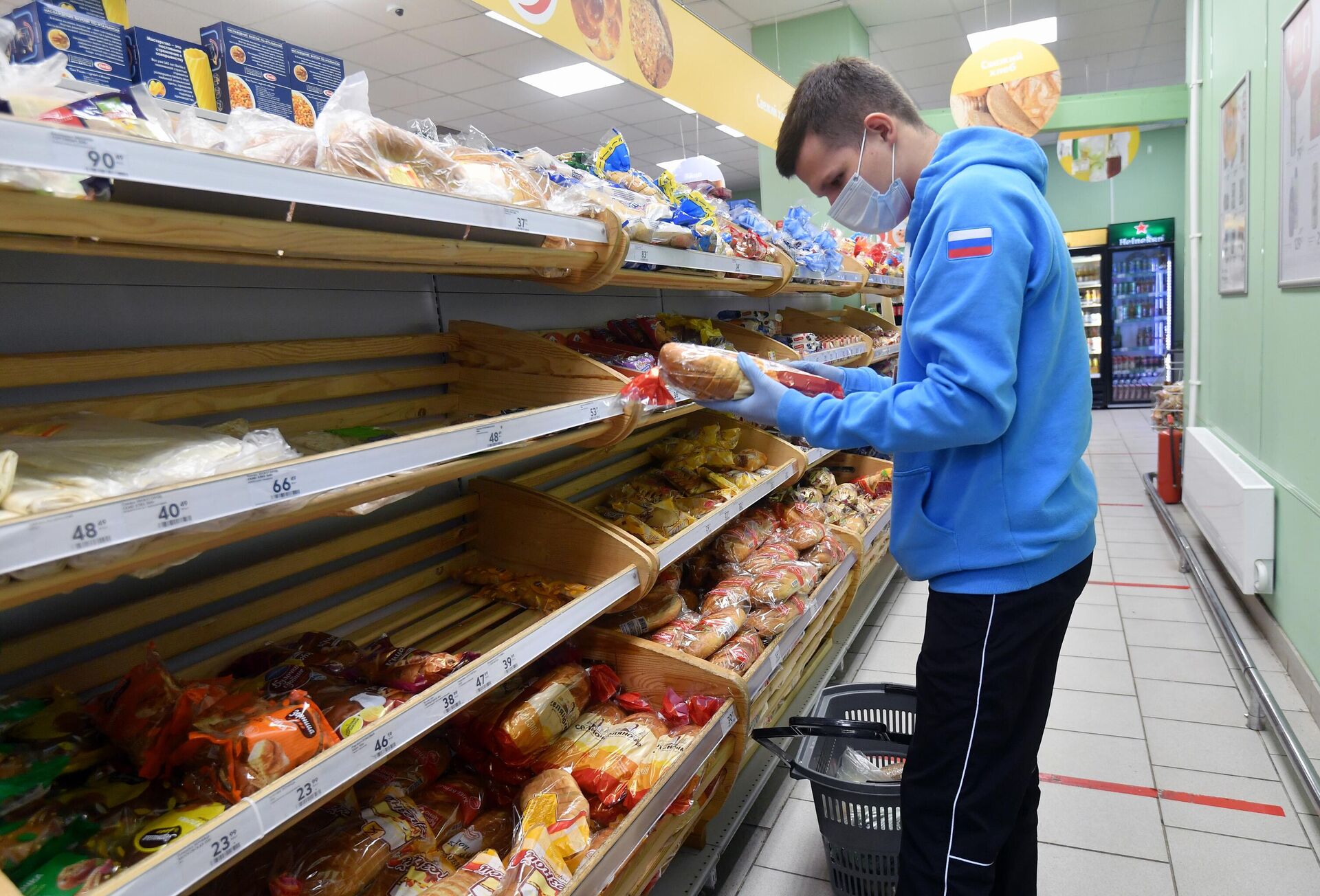 Волонтёр выбирает хлеб для пенсионеров в продуктовом магазине Москвы - РИА Новости, 1920, 26.10.2020
