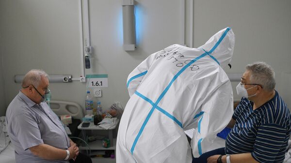 Медицинский работник и пациенты в палате временного госпиталя для пациентов с COVID-19 в автомобильном торговом центре Москва