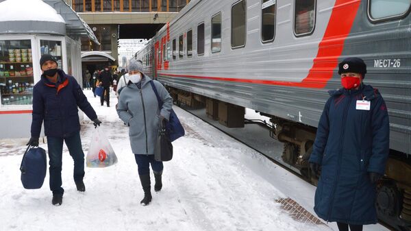 Пассажиры и проводница в защитных масках на перроне железнодорожного вокзала в Челябинске
