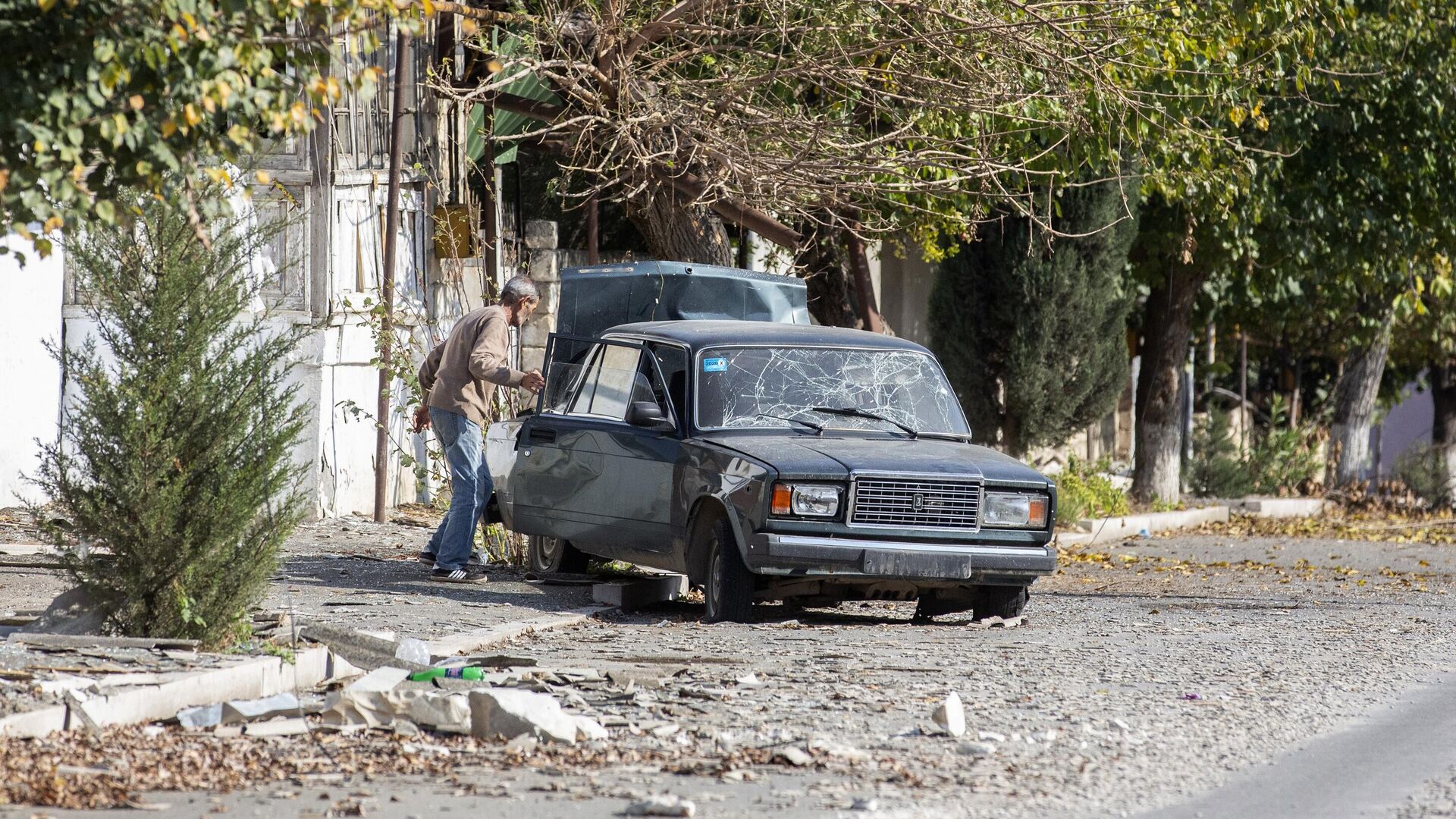 Мужчина у автомобиля, поврежденного в результате обстрелов города Мартуни в Нагорном Карабахе - РИА Новости, 1920, 31.10.2020