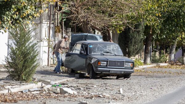 Мужчина у автомобиля, поврежденного в результате обстрелов города Мартуни в Нагорном Карабахе