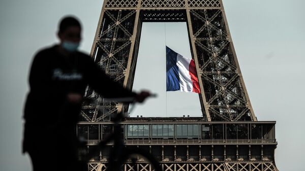 Мужчина проезжает мимо Эйфелевой башни в Париже 