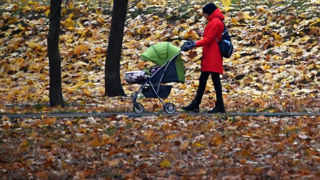 Женщина с детской коляской гуляет в сквере на Ленинском проспекте в Москве