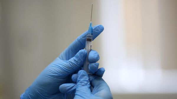 Медсестра держит шприц перед вакцинацией от коронавируса пациента в