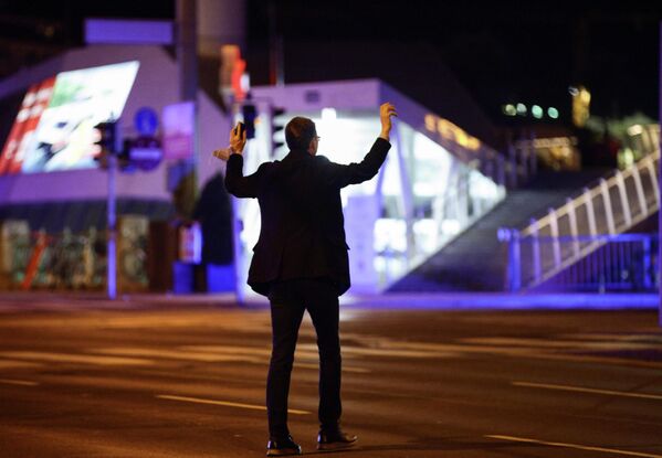 Мужчина держит руки вверх, пока полицейские проверяют его на улице после перестрелки в Вене, Австрия