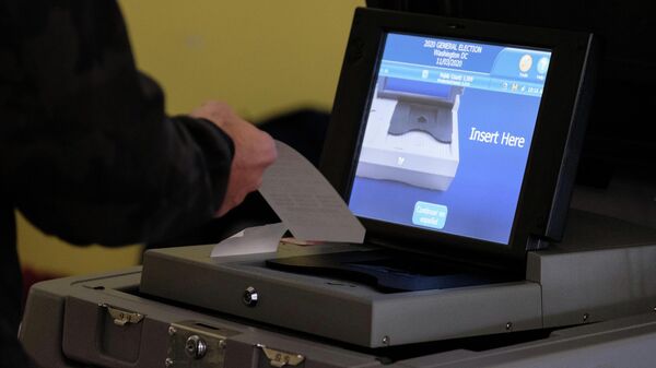 Избиратель опускает бюллетень в урну для голосования на одном из избирательных участков в Вашингтоне
