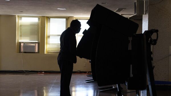 Избиратель опускает бюллетень в урну для голосования на одном из избирательных участков в ВашингтонеА