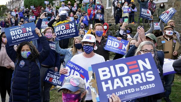 Сторонники Джо Байдена держат плакаты на избирательном участке в Филадельфии, США