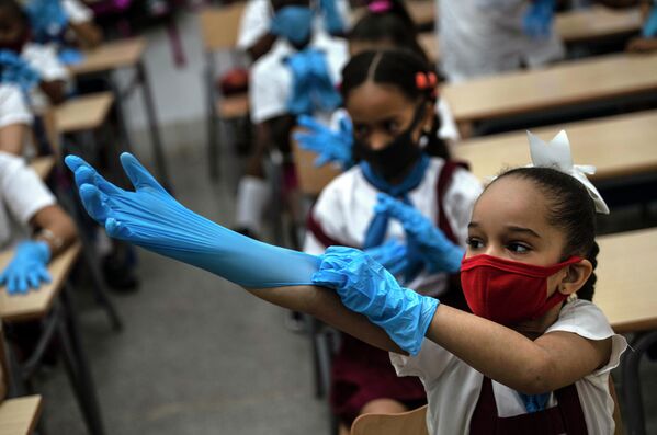 Школьница надевает перчатки в классе в Гаване, Куба