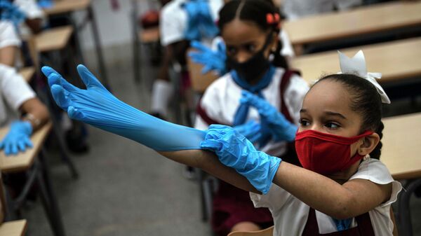 Школьница надевает перчатки в классе в Гаване, Куба