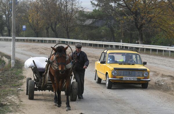 Сельский житель с повозкой запряженной лошадью и автомобиль на дороге в селе Плоп-Штюбей в Молдавии