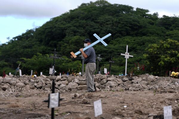 Мужчина с крестом на кладбище в День мертвых в Гондурасе