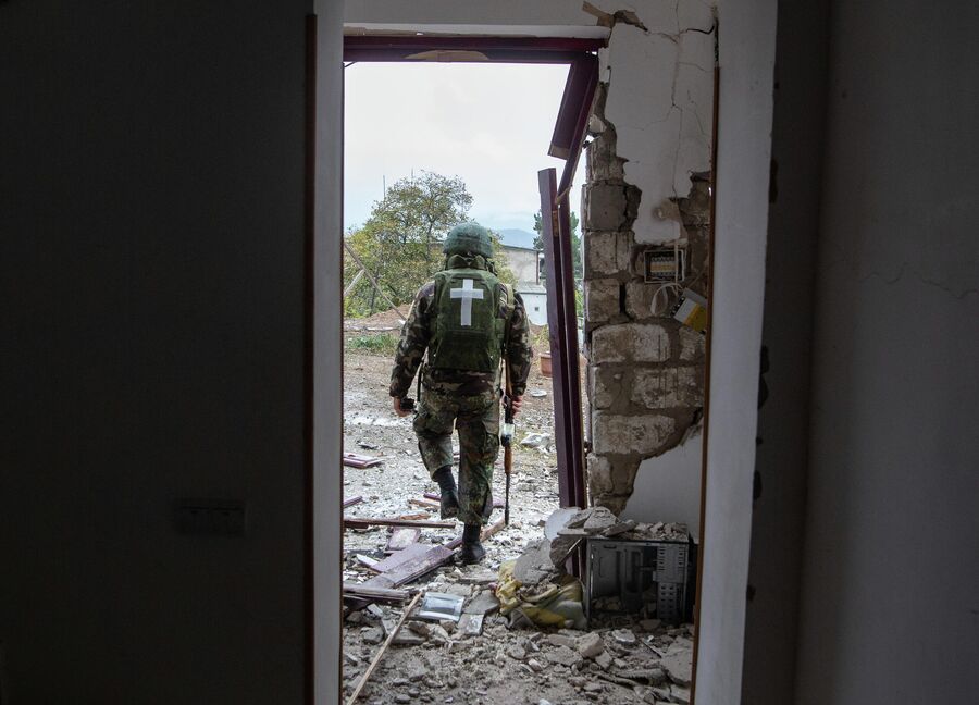 Военнослужащий возле дома, поврежденного в результате обстрела Степанакерта