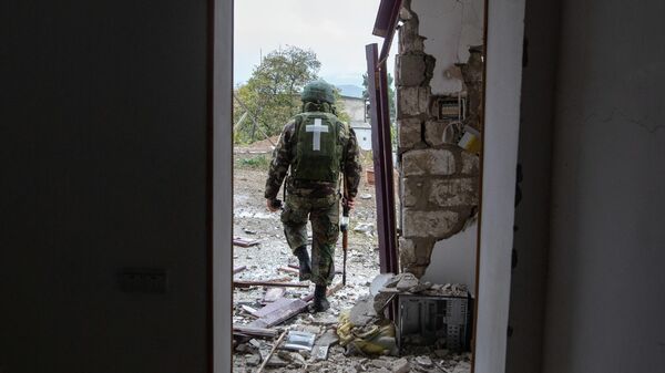 Военнослужащий возле дома, поврежденного в результате обстрела Степанакерта