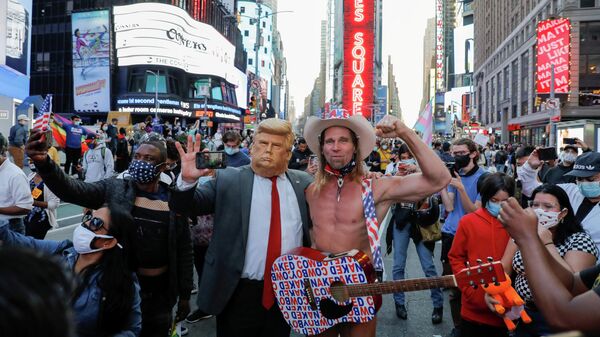 Мужчина в маске с изображением президента США Дональда и Голый ковбой празднуют победу Джо Байдена на выборах президента США в Нью-Йорке